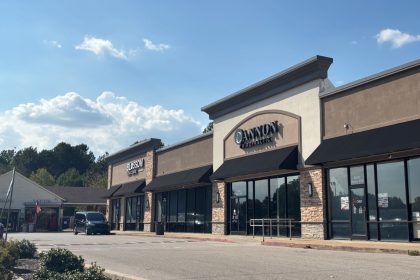 Strip mall in daylight with parked car in front.