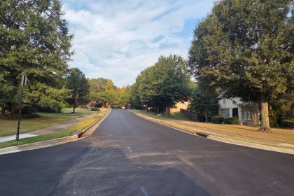 Fresh paved road on tree lined street.
