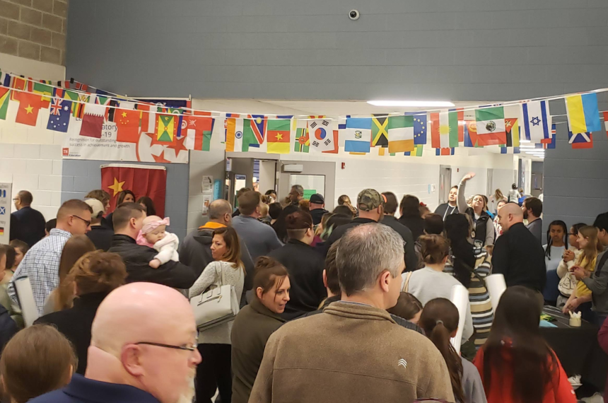 Crowd of people walking down hall of school