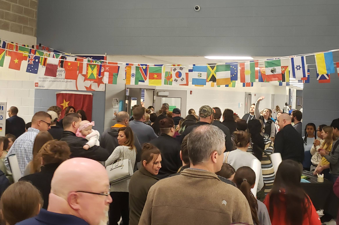 Crowd of people walking down hall of school
